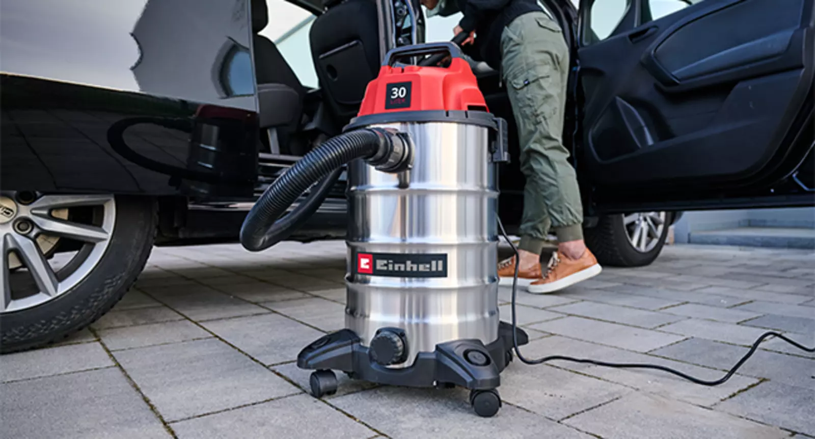 Пилосос для вологого/сухого прибирання Einhell TC-VC 3055 S використовується на вулиці для очищення автомобіля.