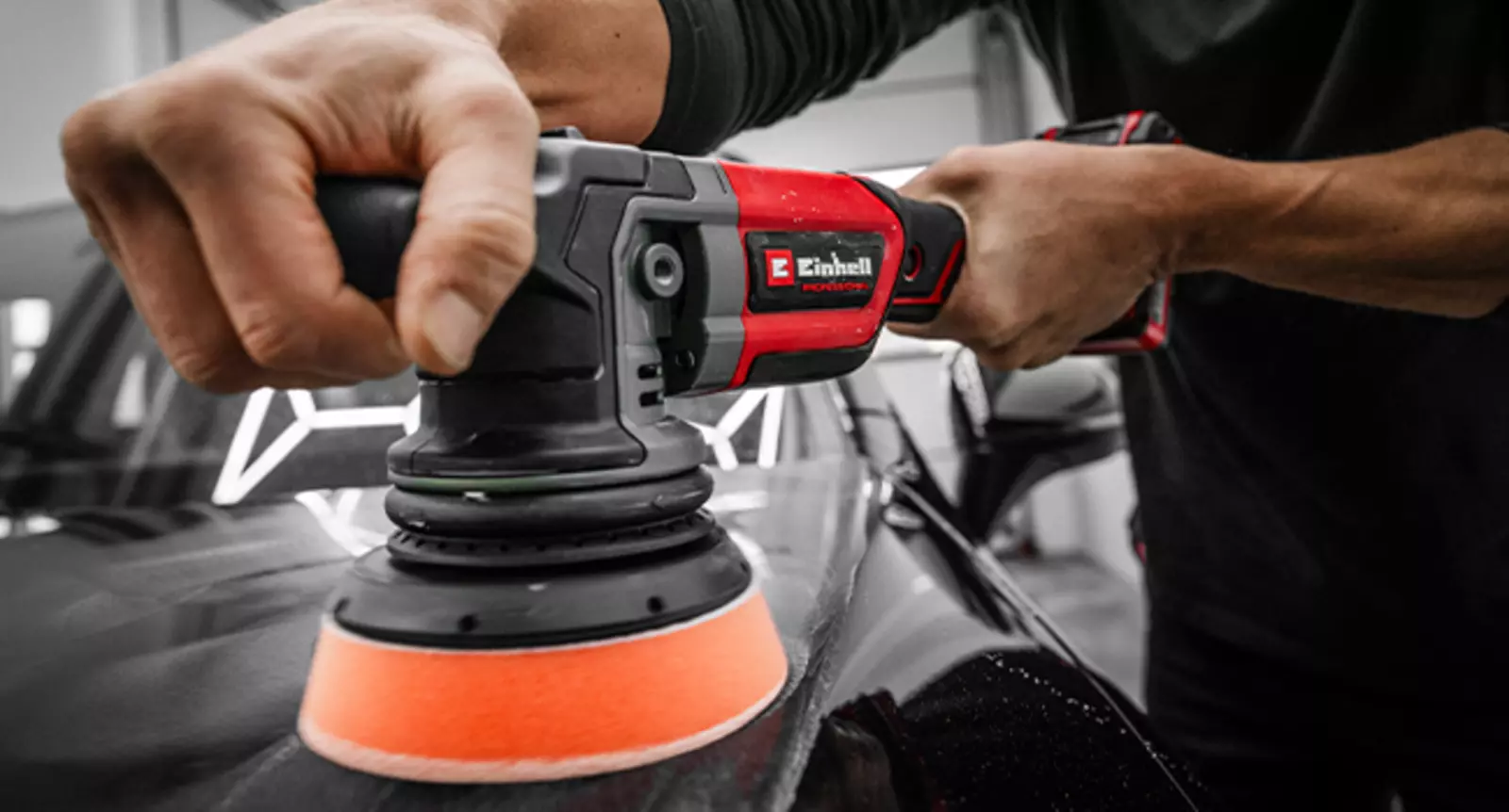 Акумуляторна ексцентрикова полірувальна машина Einhell CP-EP 18/125 Li BL-Solo використовується з помаранчевою полірувальною губкою на даху автомобіля.