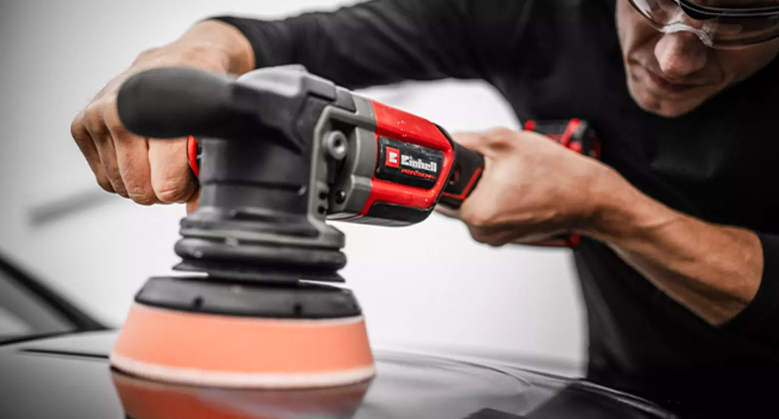 Чоловік уважно полірує поверхню автомобіля акумуляторною ексцентриковою полірувальною машинкою Einhell CP-EP 18/125 Li BL-Solo.