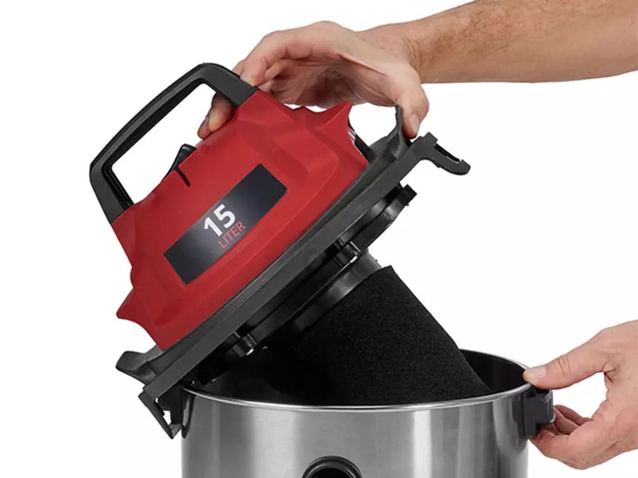 Рука піднімає моторний блок пилососа Einhell TC-VC 1540 S для спорожнення бака.