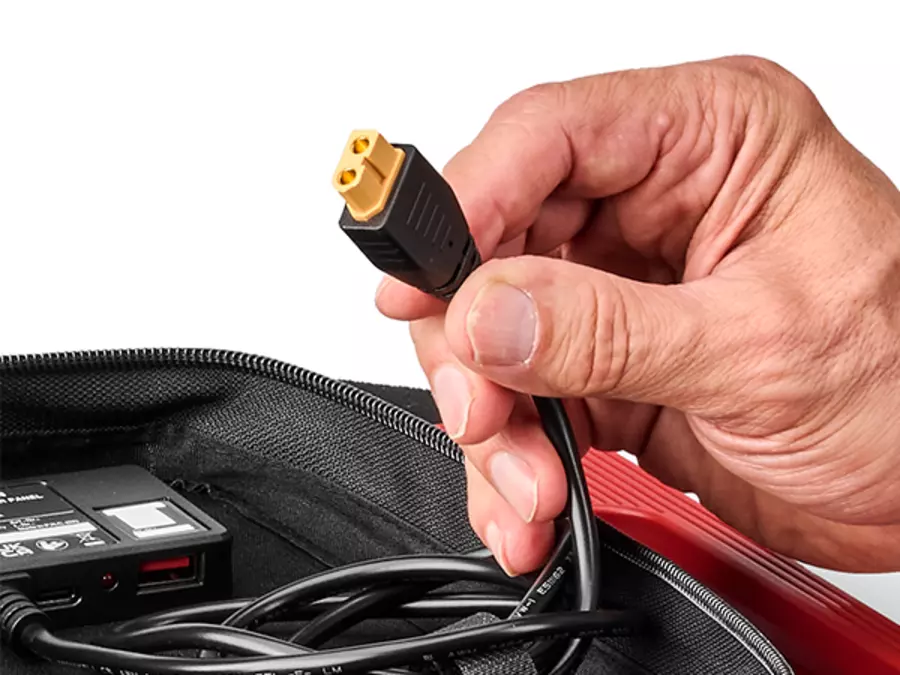 Рука держит разъем XT60 на солнечной панели Einhell для подключения к совместимым устройствам.