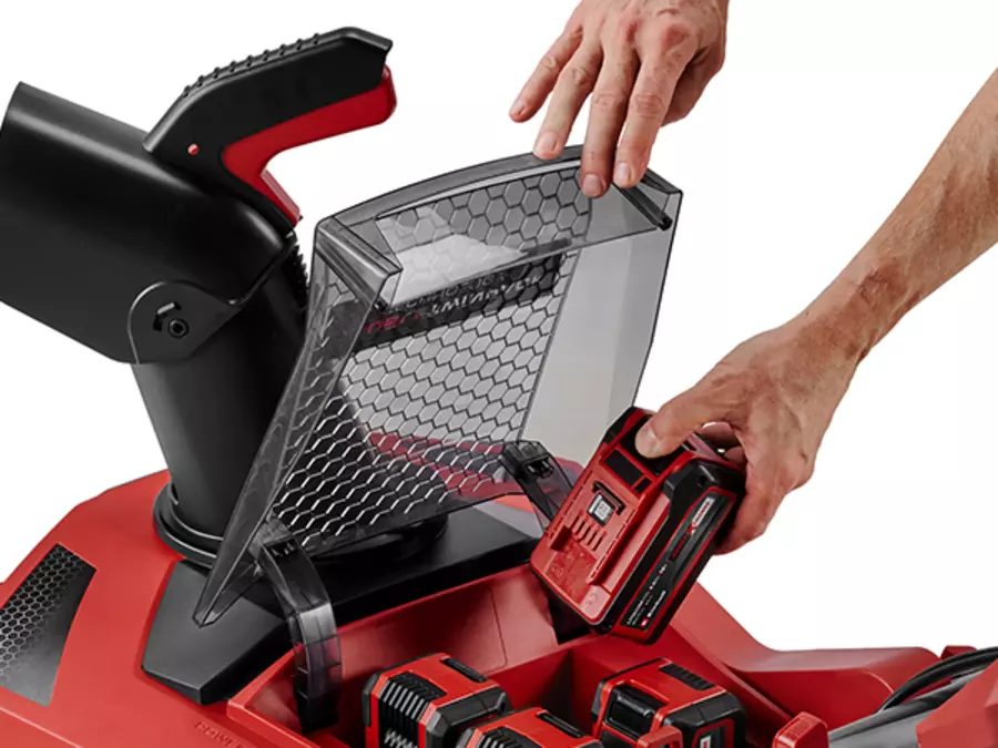 Акумуляторний снігоприбирач Einhell GP-ST 36/53 Li E BL-Solo з відкритою кришкою акумуляторного відсіку; рука тримає кришку.